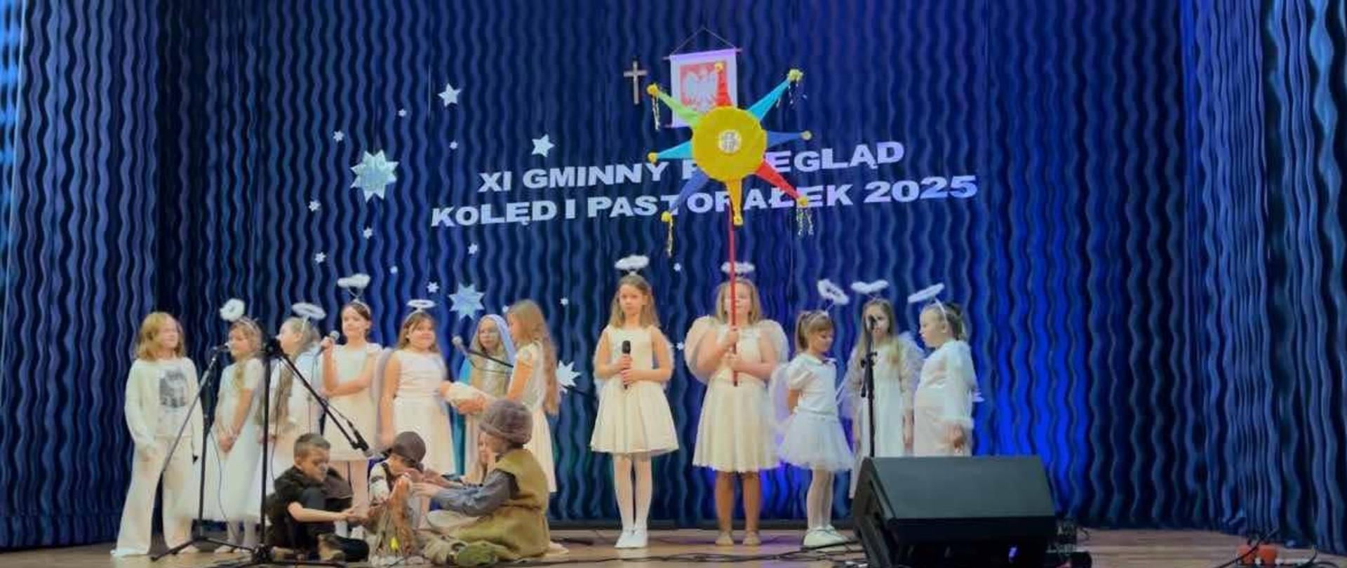 Na scenie znajduje się czworo chłopców przebranych za pastuszków. Chłopcy siedzą na podłodze i nachylają się nad atrapą ogniska. Za nimi stoi jedenaście dziewczynek ubranych w białe sukienki oraz jedna dziewczynka przebrana za Maryję. 