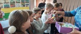 Na zdjęciu widoczni uczniowie odbierający od nauczyciela upominki.