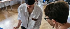 Ćwiczenia - policjantka z opaską na oczach próbuje nalać wodę do kubka