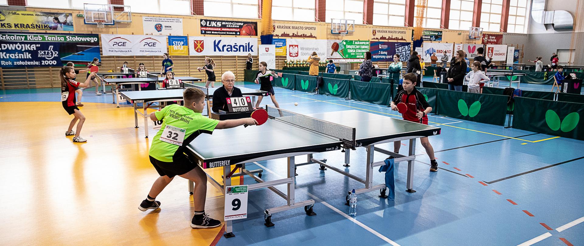 Zawodnicy podczas rozgrywanych meczy na stołach rozstawionych na hali sportowej