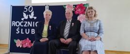 Para jubilatów Państwo Elżbieta i Eugeniusz z Wójtem Gminy na tle granatowej tablicy z napisem