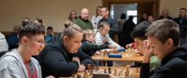 Widok z sali - przy stołach siedzą uczestnicy, rozgrywają partię szachów