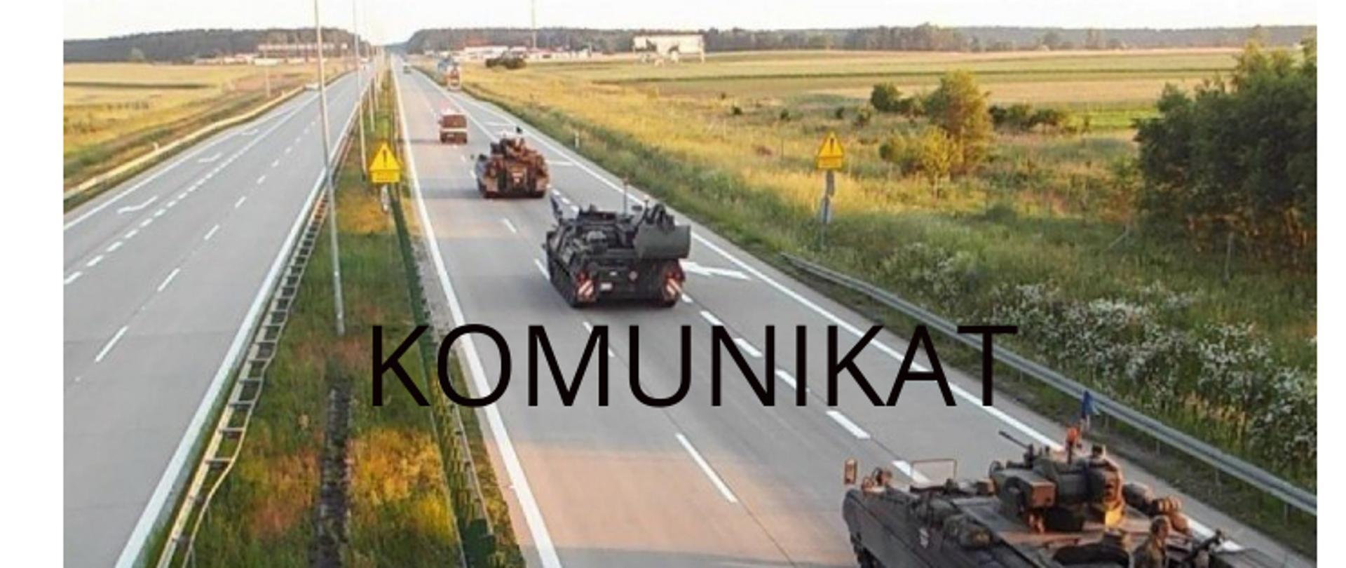 Kolumna pojazdów wojskowych jedzie autostradą w kierunku horyzontu, po prawej stronie widoczne pola i drzewa. Na środku zdjęcia umieszczony duży napis „KOMUNIKAT”.