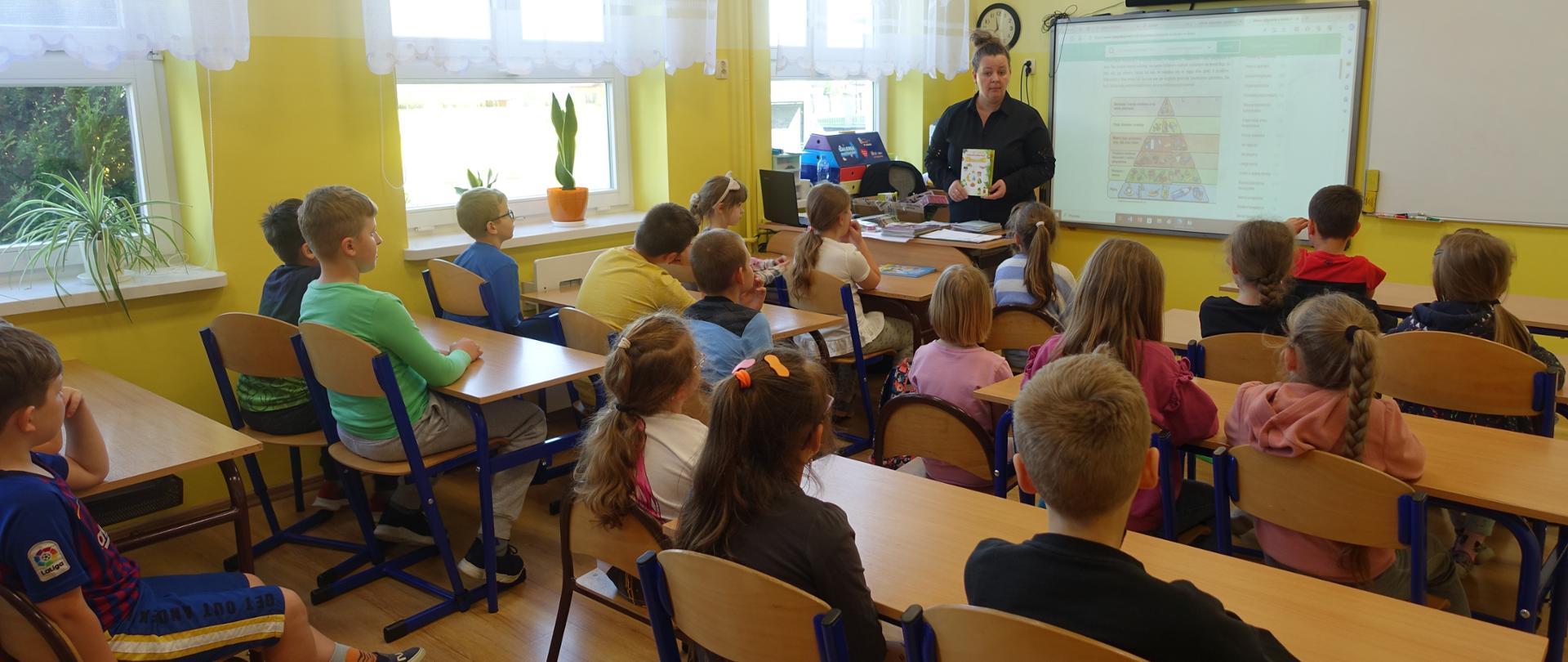 Nauczyciel w sali lekcyjnej wraz z uczniami - prelekcja.