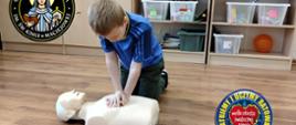 Uczeń wykonuje masaż serca na manekinie, w tle szafki klasowe z pudełkami na przybory