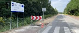 Fragment drogi powiatowej w Radgoszczy, przy której trwają prace budowlane związane z powstaniem asfaltowej ścieżki rowerowej.
