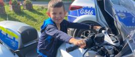 Uczeń siedzi na motocyklu policyjnym