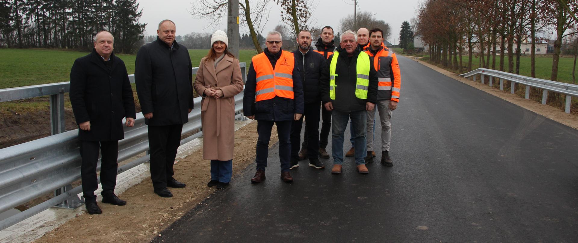 Na zdjęciu most po remoncie. Na nim od lewej: Wicestarosta Zambrowski - Robert Maciej Rosiak, Wójt Gminy Szumowo - Andrzej Pskiet, Starosta Zambrowski - Edyta Marchelska-Groszfeld, Naczelnik Wydziału Infrastruktury i Rozwoju - Zbigniew Rzepiński, Inspektor nadzoru Inwestorskiego - Paweł Sobieski, Właściciel Firmy Transportowo - Usługowej - Mirosław Przesmycki, Kierownik Budowy - Adam Przesmycki, Inspektor Wydziału Infrastruktury i Rozwoju - Wojciech Wiśniewski, Zastępca Naczelnika Wydziału Infrastruktury i Rozwoju - Paweł Tabędzki.