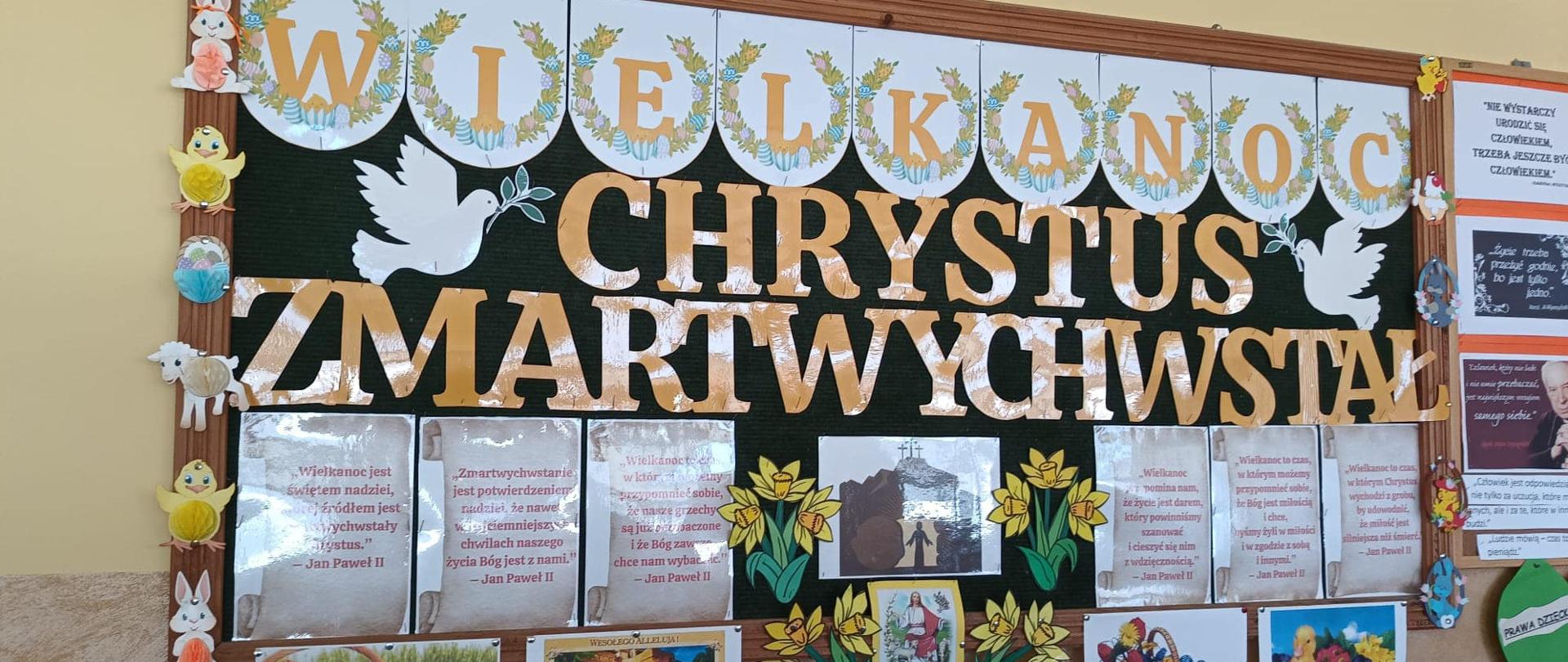 Kolorowa gazetka ścienna z napisem Wielkanoc i Chrystus Zmartwychwstał, ozdobiona zdjęciami jajeczek, kurczaczków, baranków, kwiatów