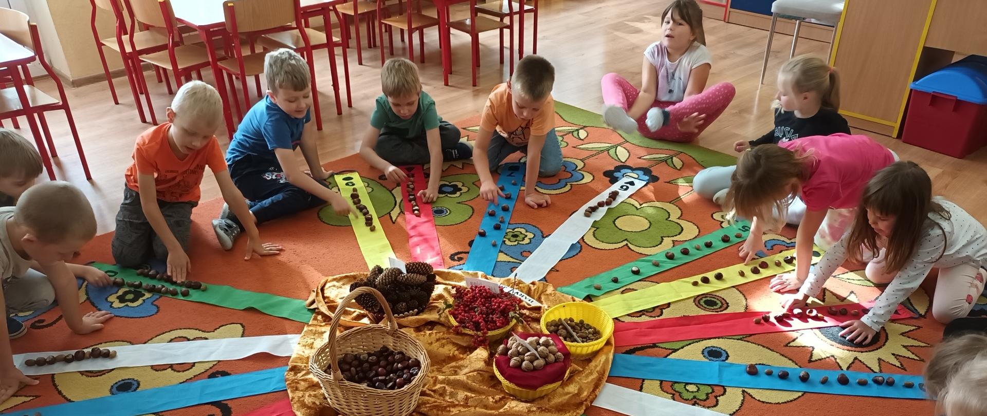 grupa dzieci bawi sie kasztanami