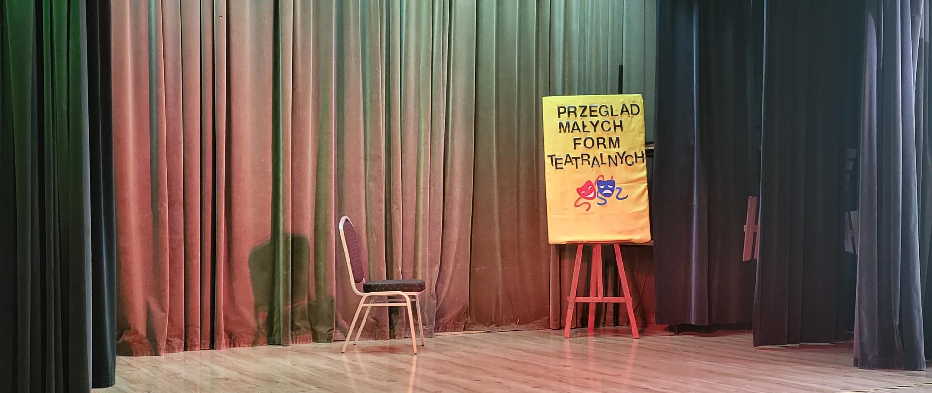 Na pustej scenie krzesło i napis Przegląd Małych Form Teatralnych