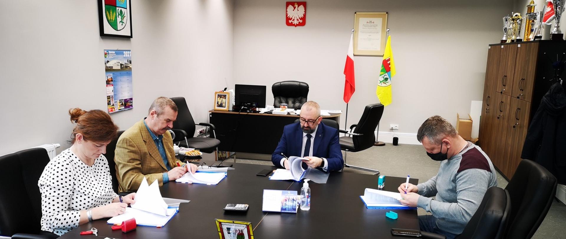 Zdjęcie przedstawia gabinet Starosty Przasnyskiego w trakcie podpisywania umowy na przebudowę chodnika przy ulicy Baranowskiej w Przasnyszu. Od lewej Skarbnik Powiatu Przasnyskiego Beata Czaplicka, Wicestarosta Waldemar Trochimiuk, Starosta Krzysztof Bieńkowski, wykonawca reprezentujący firmę ROMA Przedsiębiorstwo Realizacji Inwestycji - Mariusz Bartkowicz.