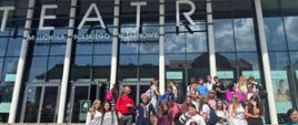 Uczniowie wraz z opiekunami stoją na schodach przed wejściem do teatru