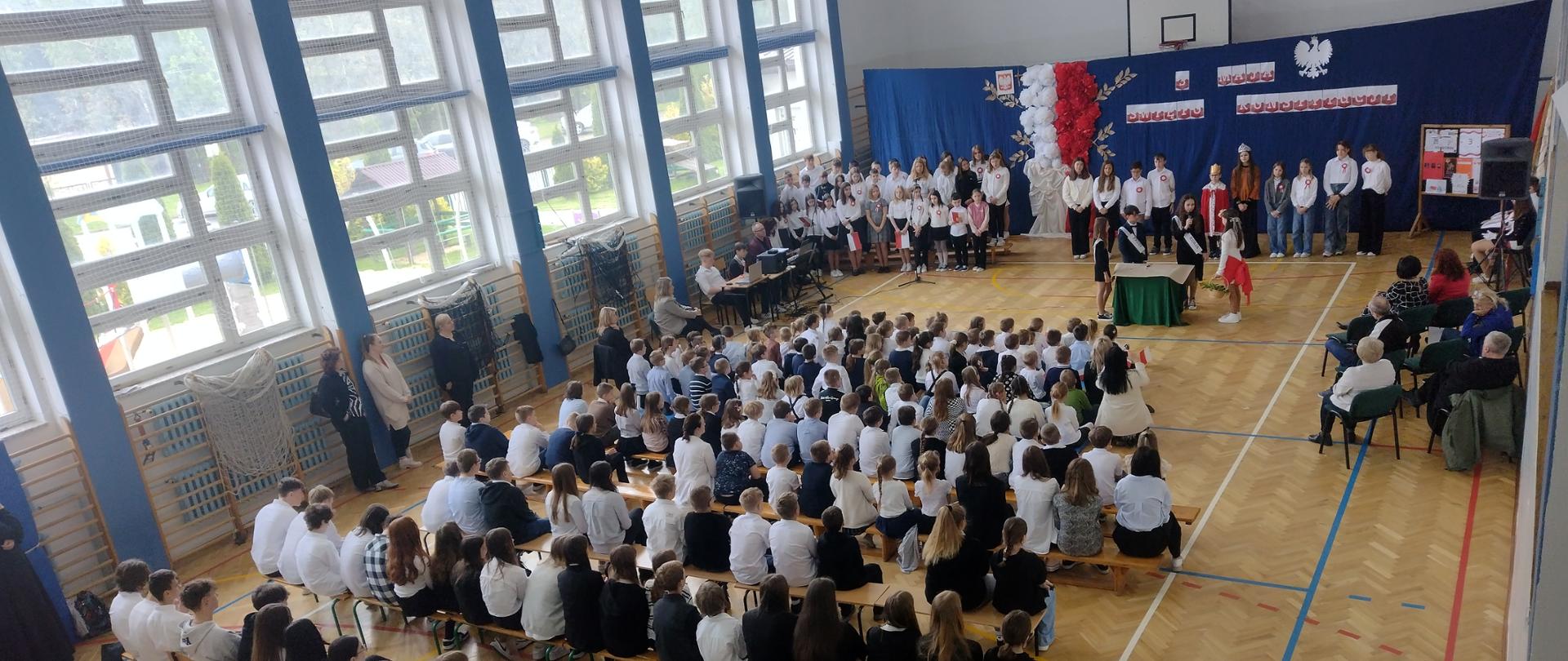 Uczniowie i nauczyciele oglądają uroczystą akademię