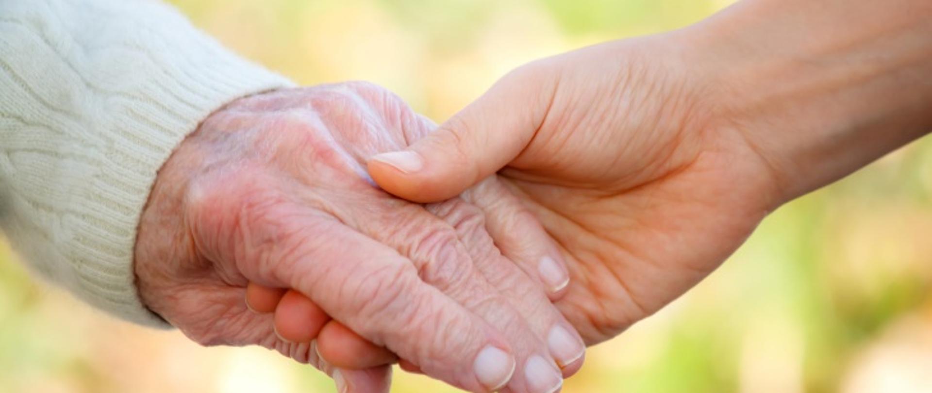 Senior and young holding hands outside