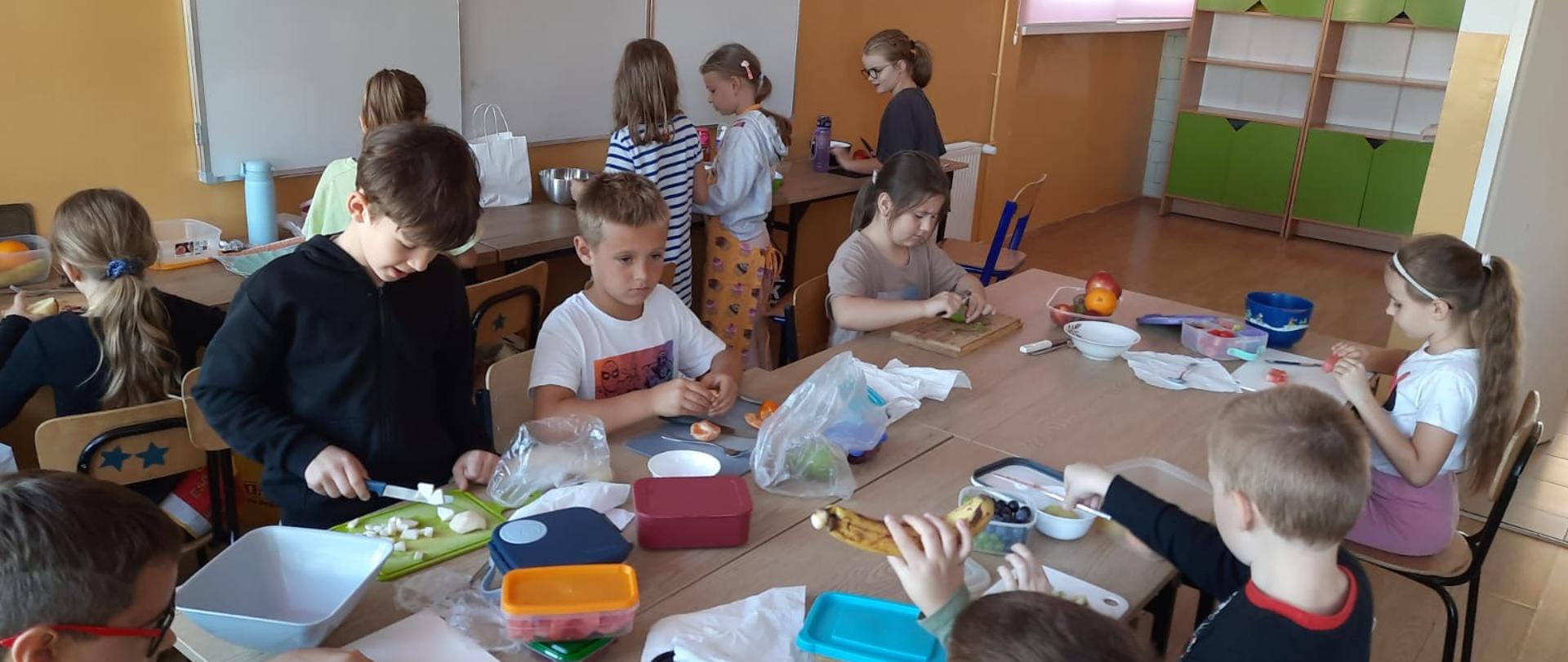 Uczniowie klasy 2a wykonują sałatkę owocową.
