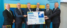 mężczyźni w garniturach trzymający razem tablicę, wewnątrz