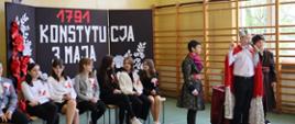 Inscenizacja artystyczna z okazji święta Konstytucji 3 Maja. Uczniowie w kostiumach króla, szlachty i mieszczaństwa.