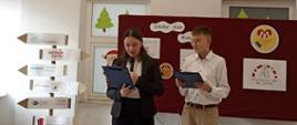 Od lewej uczennica i uczeń z klasy 8 prowadzą pasowanie na wolontariuszy, przemawiają do mikrofonu