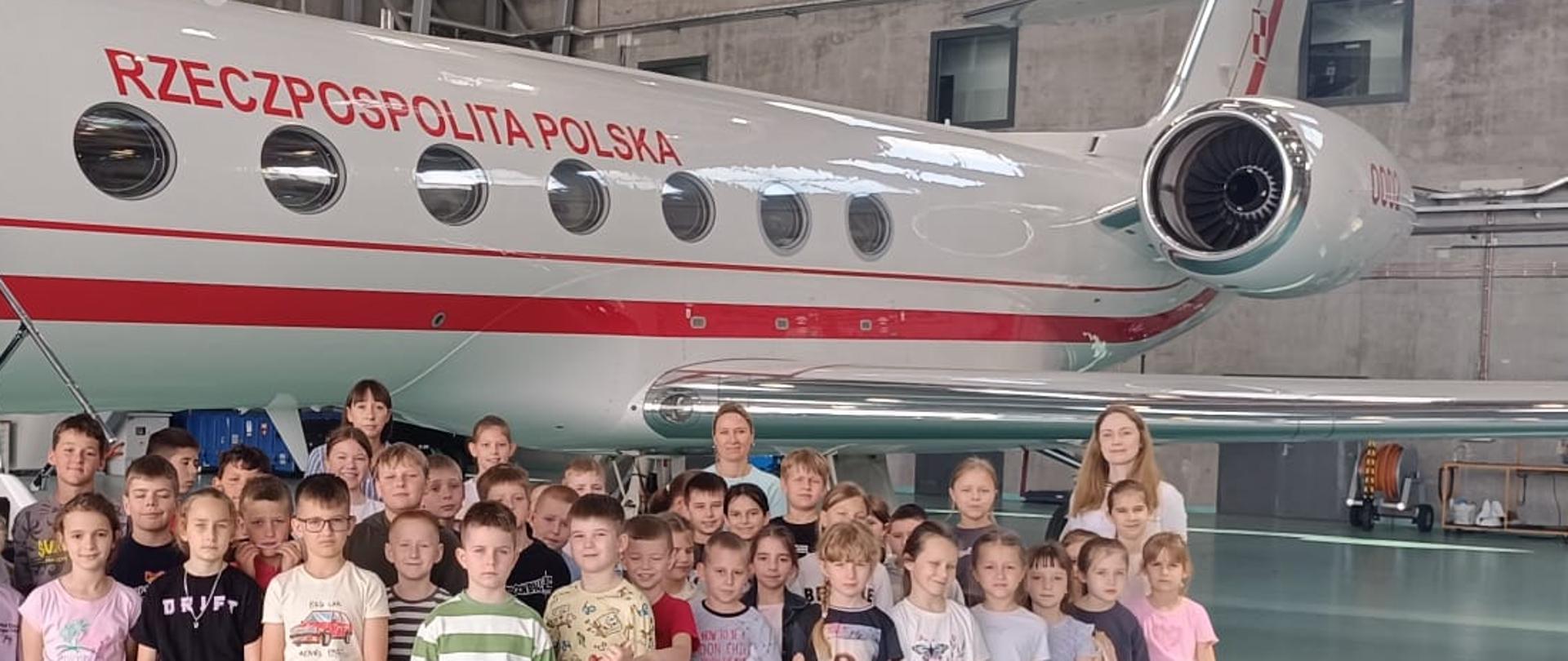 uczniowie podczas wycieczki szkolnej pozują na tle prezydenckiego samolotu