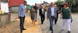 Mężczyźni i kobiety spacerujący wzdłuż drogi. 