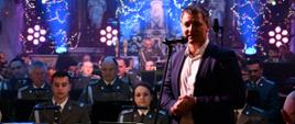 orkiestra w mundurach siedząca w kościele, w tle ołtarz, na pierwszym planie zastępca burmistrza Miasta i Gminy Margonin
