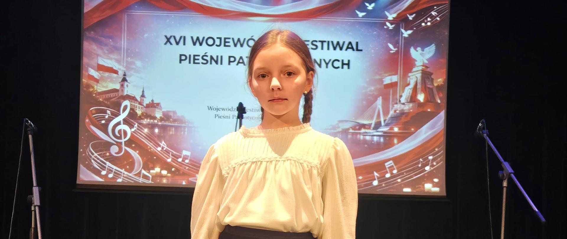 Uczennica klasy 3 a na tle baneru konkursowego.