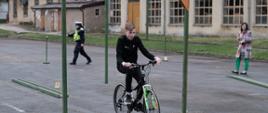 Uczeń na rowerze wykonuje ćwiczenia praktyczne na wyznaczonym torze