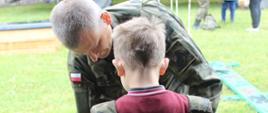 Żołnierz nakłada na chłopca wojskową kamizelkę
