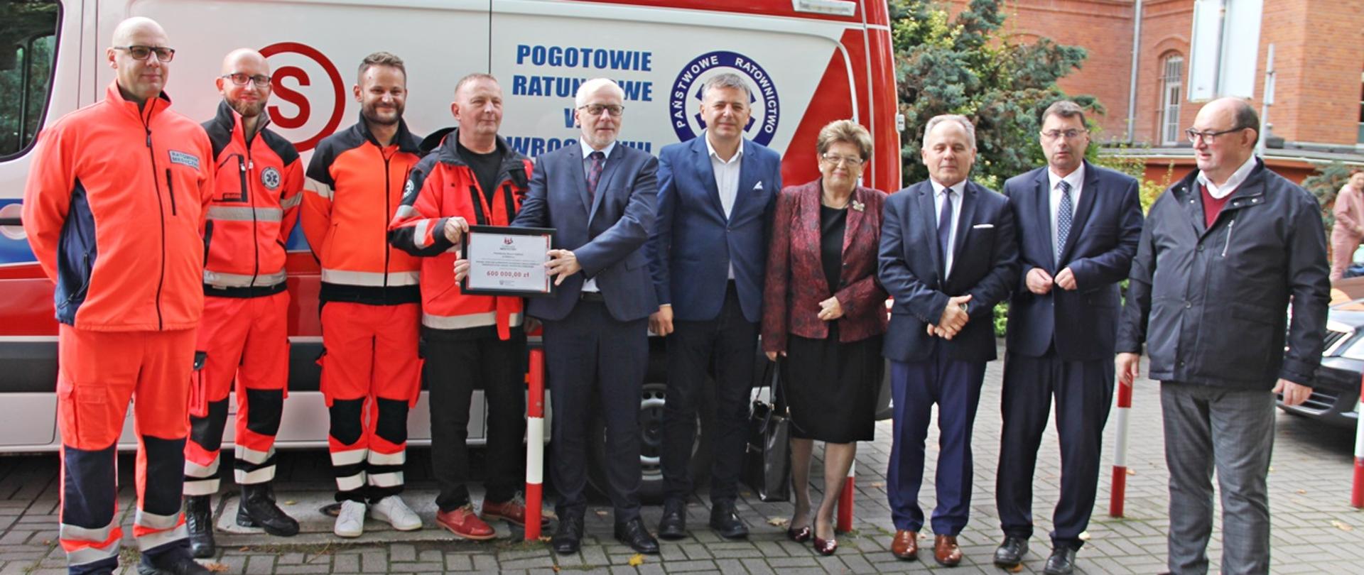 Uczestnicy przekazania czeku stoją pod szpitalem