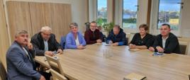 dwie kobiety i pięciu mężczyzn siedzą przy wspólnym stole 