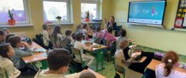 Uczniowie klas 1-3 siedzą w ławkach, oglądają prezentację i słuchają pogadanki prowadzonej przez panią pedagog