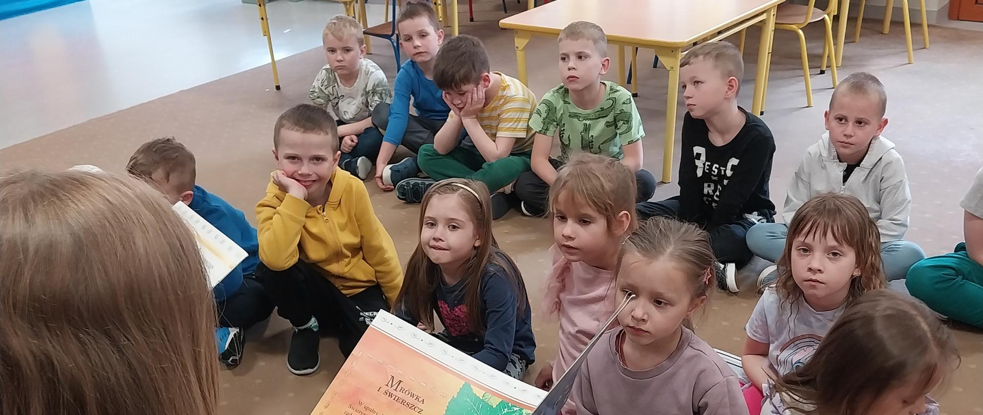 uczniowie starszych klas czytają bajki przedszkolakom