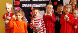 Dzieci prezentujące różne atrybuty walentynkowe takie jak okulary w kształcie serc, usta, wąsy, kapelusz