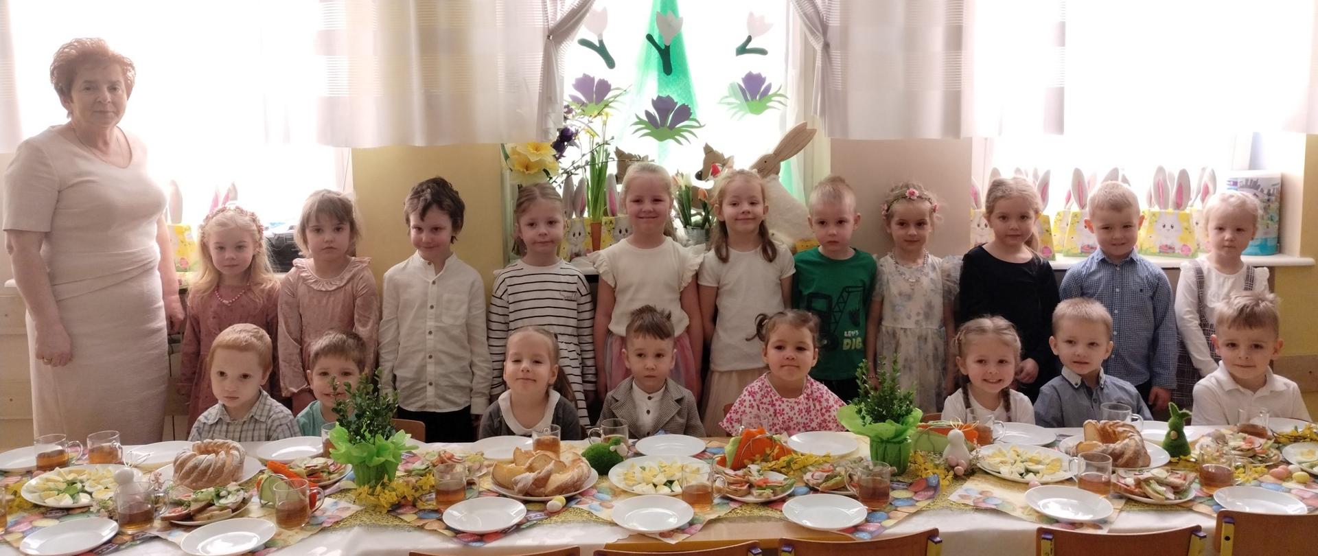 Dzieci i 1 kobieta przy stole z potrawami wielkanocnyni