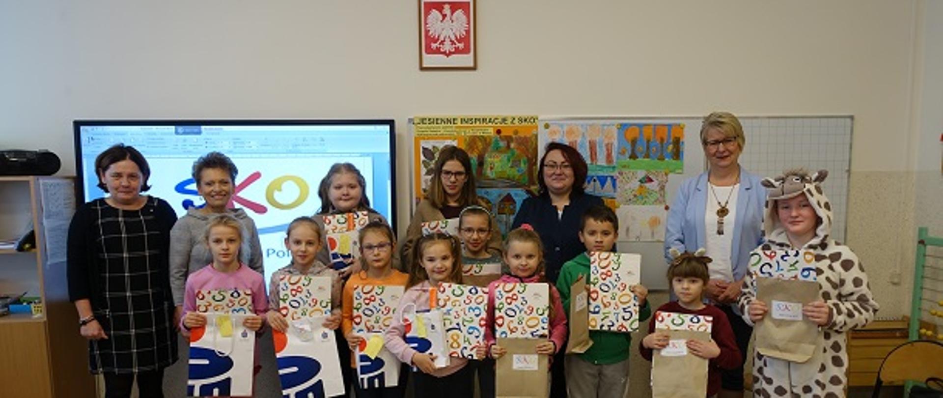 Dyrektor szkoły, opiekunka SKO, panie z banku oraz uczniowie nagrodzeni w szkolnym konkursie plastycznym "Jesienne inspiracje".