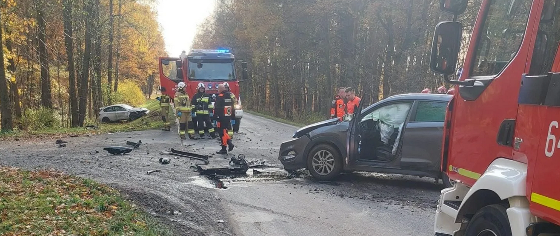 Rozbite samochody przy których stoją wozy strażackie i służby ratownicze.