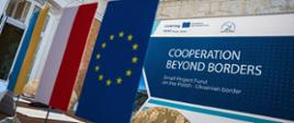 Za stołem, na którym umieszczono folgi Ukrainy, Polski i Unii Europejskiej, stoi baner promujący Euroregion Karpacki