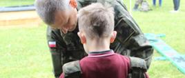 Żołnierz nakłada na chłopca wojskową kamizelkę