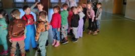 Dzieci stoją w rzędzie na szkolnym korytarzu