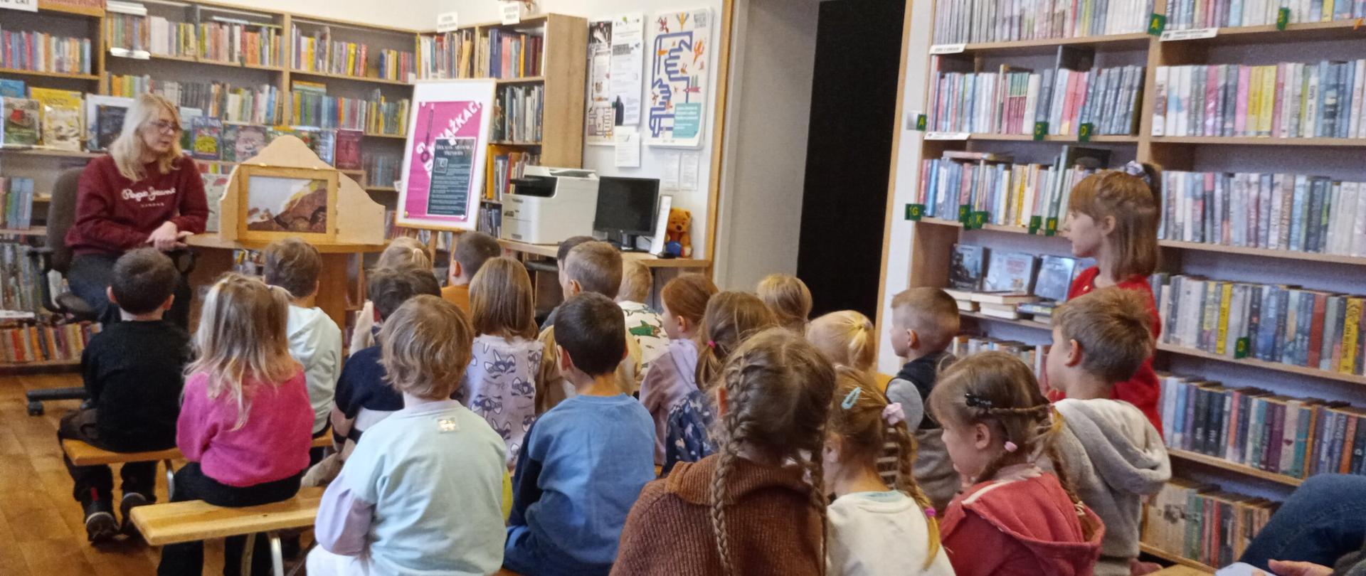 Zdjęcie przestawia dzieci, które uczestniczą w zajęciach bibliotecznych