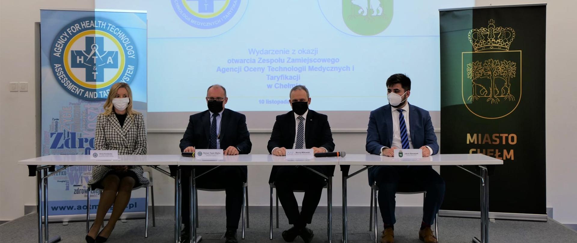 Cztery osoby siedzą za stołem wewnątrz budynku.