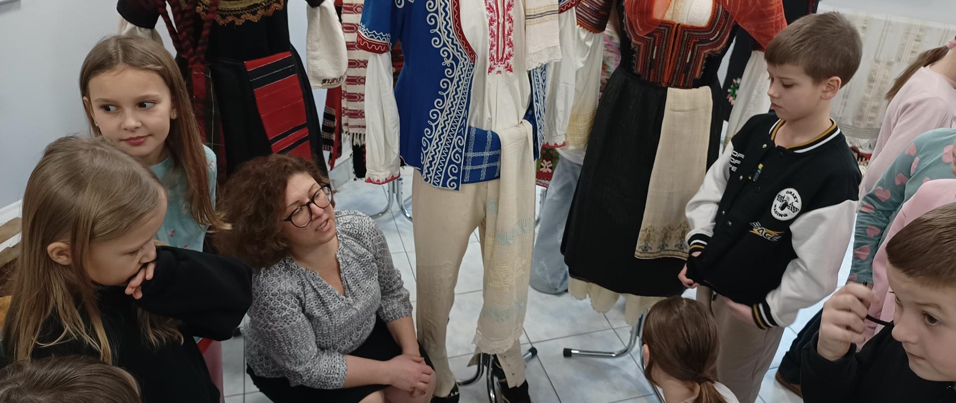 Kobieta kuca przy manekinach ubranych w stroje ludowe