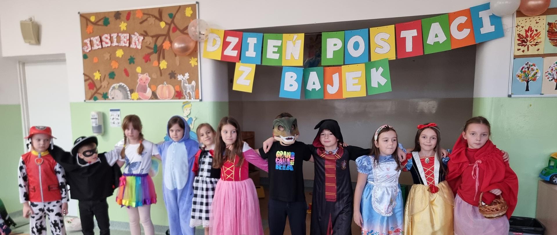 Kolorowa dekoracja z napisem „Dzień Postaci z Bajek”. Pod nim znajduje się materiał z ilustracją bohaterów z bajki, w którym dzieci mogą włożyć twarze i zrobić zdjęcie.