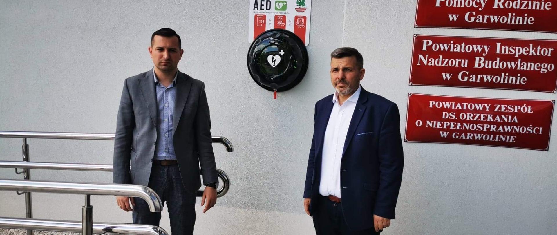 Starosta i Wicestarosta przy ścianie budynku starostwa, gdzie zawieszony jest defibrylator