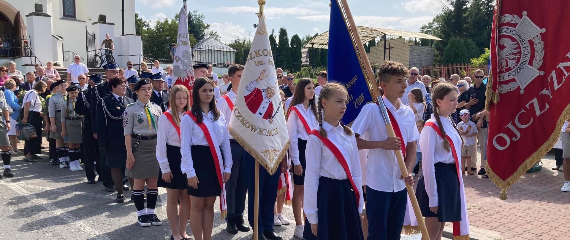 procesja przed kościołem z pocztem sztandarowym