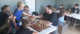 Uczestnicy siedzą przy szachach, rozgrywają potyczki