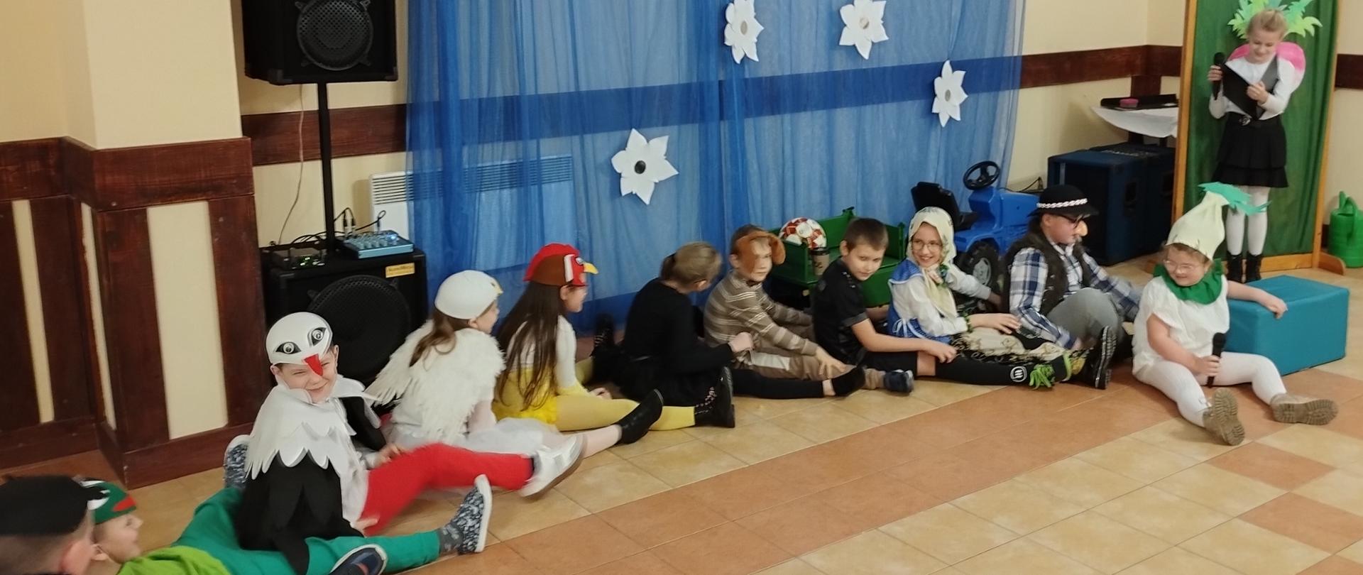 Aktorzy biorący udział w przedstawieniu "Rzepka" siedzą na scenie.