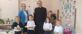 Nagrodzone w konkursie dzieci stoją w klasie, trzymają w ręku nagrody, za nimi od lewej Pani Dyrektor Szkoły i Ksiądz