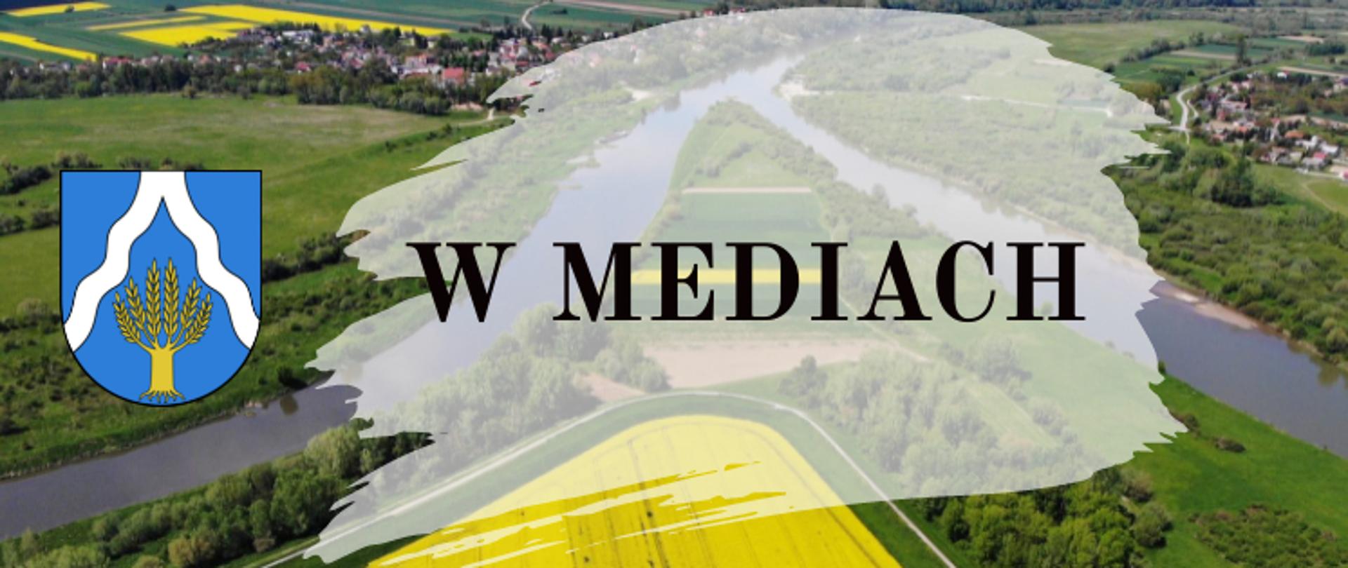 LOGO- napis W MEDIACH na tle zdjęcia Cyplu, po lewej stronie napisu herb Gminy Wietrzychowice